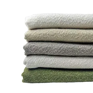 Macro detail of thick bouclé yarn fabric stack in neutral earth tones for sofa and cushions