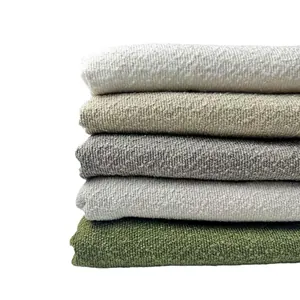 Stacked thick bouclé yarn sofa fabric swatches in neutral earth tones and olive green