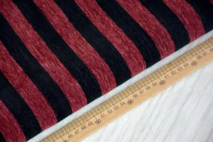 Primo piano di tessuto ciniglia a righe rosse e nere con righello in legno per scala.