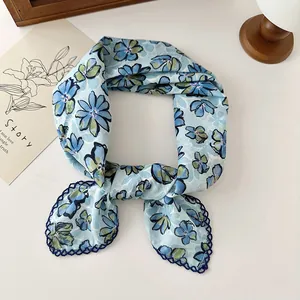 Detail of a light blue cotton neckerchief featuring vintage daisy prints and lace trim.