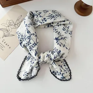 Detail shot of vintage cotton square scarf with blue floral print and lace trim.