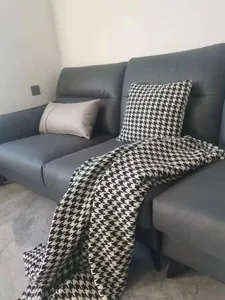 Classic black and white houndstooth chenille fabric throw and pillow on grey sofa