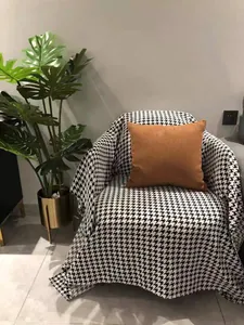 Classic black and white houndstooth fabric draped over a sofa with a brown decorative pillow