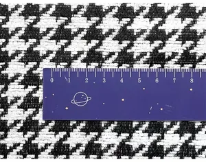 Macro view of black and white houndstooth chenille fabric with a ruler for scale