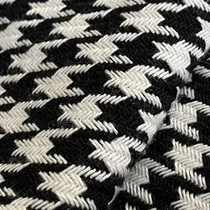 Macro detail showing the rich woven texture of black and white houndstooth chenille fabric.