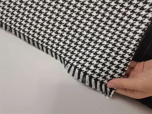 Detailed view of black and white houndstooth chenille fabric featuring elegant fringed edges.