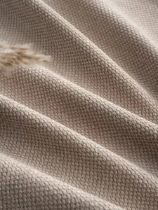 Macro detail of soft beige chenille fabric texture with natural drapery folds.