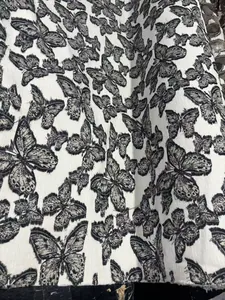 Vue détaillée du tissu jacquard chenille blanc avec motif papillon à franges 3D