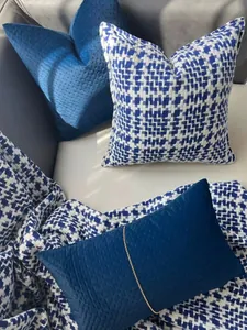 Detailed view of blue velvet and navy blue houndstooth woven decorative pillows on sofa