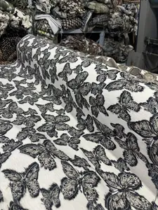 Gros plan sur un tissu chenille jacquard blanc avec motif papillon noir 3D