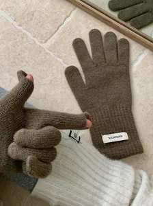 Detail of olive green merino wool knitted gloves with 100% wool label for winter