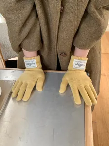 Detailed view of yellow knitted winter gloves with vintage brand label on the cuff