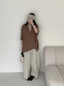 Modella che indossa un cardigan in maglia marrone in un ambiente minimalista