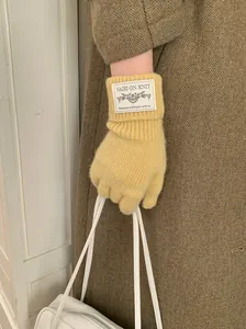 Detailed view of yellow knitted winter gloves with a white brand patch on the cuff