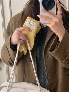 Close-up of yellow knitted winter gloves held in a lifestyle mirror selfie