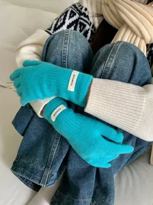 Close-up of bright teal Merino wool gloves featuring a 100% wool label for winter.