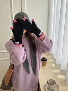 Close-up of stylish black coral fleece winter gloves with pink fingertips on a model