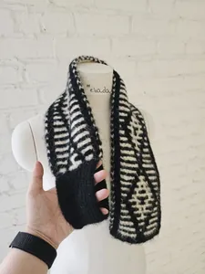 Close-up detail of a soft black and white striped knitted scarf with geometric patterns
