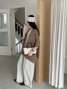 Elegant retro brown knit shawl cape shown on a model in a minimalist interior setting