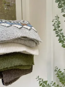 Stack of cozy Fair Isle jacquard and solid color knitted scarves in earthy tones