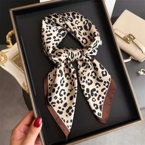 Close-up of elegant leopard print silk scarf tied in a bow on black tray