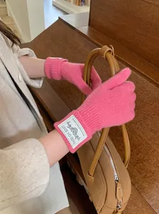 Detail view of soft pink knitted gloves featuring a white label and warm winter texture.