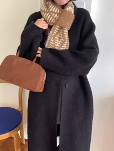 Elegant brown cross-knit patterned scarf styled with a black coat and suede handbag
