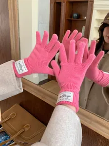 Close-up of pink knitted winter gloves featuring a stylish woven brand label detail