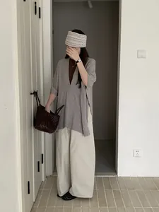 Modella indossa uno scialle di maglia grigio retrò con pantaloni larghi beige per l'autunno