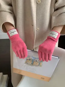 Close-up of pink knitted winter gloves with a stylish woven label on the wrist
