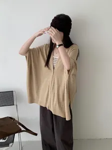 Vista dettagliata di un poncho in maglia kaki retrò sopra un top a righe per l'autunno.