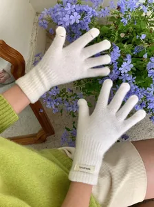 Detail view of 100% wool white knitted gloves with touch screen finger openings.