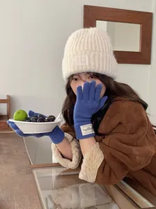 Detailed view of warm blue knit gloves for winter worn by model with matching beanie