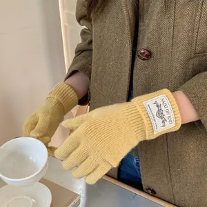 Warm yellow knitted winter gloves with touch screen finger tips and a cozy fabric label