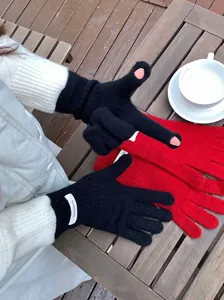 Detailed view of the 100% wool label and touchscreen finger openings on black knit gloves