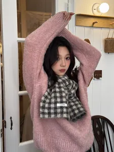 Chic black and white checkered knit scarf styled with a cozy pink knitted sweater detail