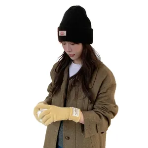 Warm yellow knitted touchscreen gloves and black beanie on Asian model