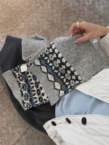 Close-up detail showing texture of Fair Isle patterned knit scarf with vintage leather tag