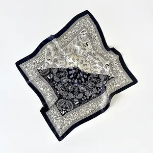 Dettaglio ravvicinato di sciarpa in seta vintage con motivo paisley nero e crema e pieghe