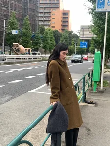 Woman wearing a thick grey wool scarf paired with a stylish brown wool coat in urban street