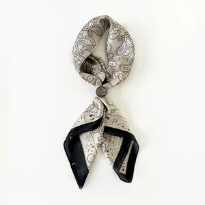 Dettaglio di un foulard in seta vintage con motivo paisley e fibbia in metallo