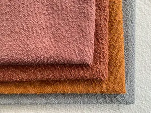 Dettaglio di tessuti bouclé spessi in rosa, ruggine, arancione e grigio per divani