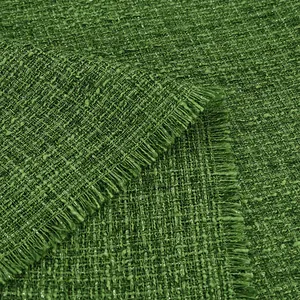 Close-up of green bouclé tweed fabric with textured wave pattern and frayed edges