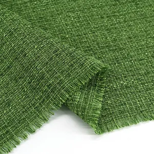 Close-up of green tweed fabric texture with silver metallic threads and frayed edges