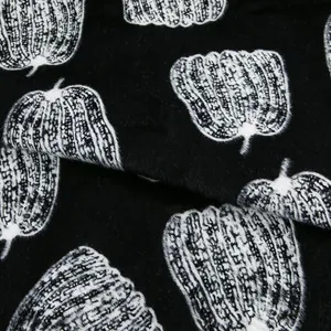 Vue détaillée du tissu en velours de vison noir avec des motifs citrouille blancs