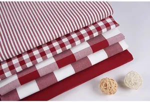 Detailed view of stacked red and white plaid and striped linen-like craft fabrics