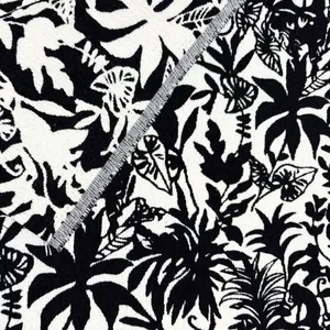 Primo piano del motivo a foglie tropicali bianco e nero su tessuto jacquard di ciniglia.