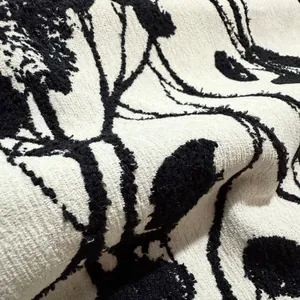 Macro dettaglio di tessuto jacquard ciniglia bianco e nero con motivo vegetale astratto.