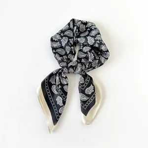 Primo piano di un foulard vintage in seta nera con motivo paisley e bordi crema