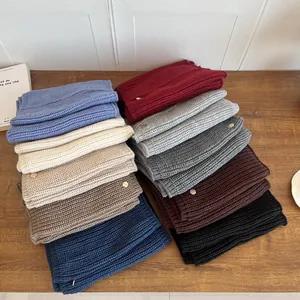 Macro view of thick knit neck gaiters in various winter colors with metal tags
